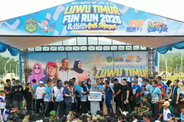 Gubernur Sulawesi Selatan, Andi Sudirman Sulaiman, menyerahkan hadiah umrah kepada Nurlina, bidan PNS dari UPTD Puskesmas Berau, yang tak kuasa menahan tangis haru setelah namanya diumumkan sebagai pemenang undian dalam acara Fun Run Luwu Timur 2025 dan Gerakan Anti Mager Sulsel, Minggu (18/5/2025).