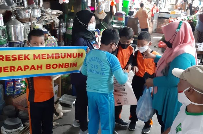 PD Pasar Surya, DLH Surabaya, Komunitas Nol Sampah bersama siswa SDN Kertajaya IV saat melakukan aksi bagi-bagi kantong non-plastik di Pasar Pucang Anom.