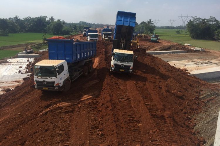 Sejumlah truk mengangkut material pasir yang digunakan untuk menguruk Jembatan Sereng Baru pada pekerjaan Paket 3 Tol Pemalang-Batang, Sabtu (26/5/2018). (Kompas.com / Dani Prabowo)  