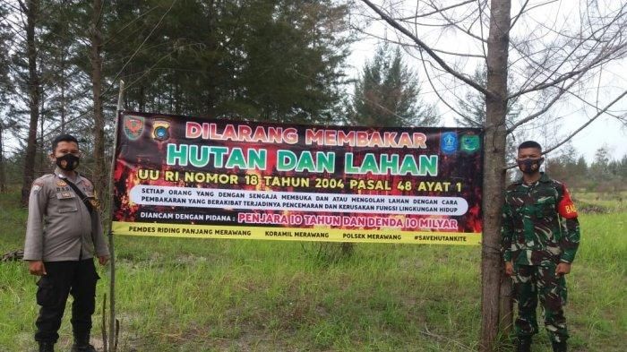 Bhabinkamtibmas Bripka Dedi Irawan dan Babinsa TNI Prada Yudikatif memasang spanduk mencegah kebakaran lahan dan hutan di Desa Ridingpanjang Kecamatan Merawang Kabupaten Bangka 