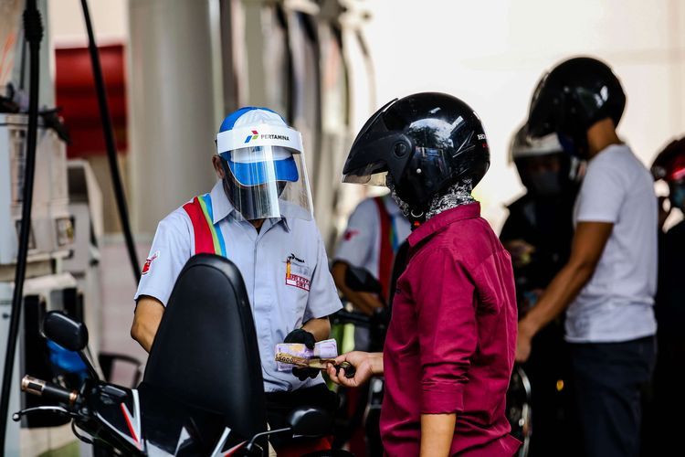 Petugas SPBU menggunakan alat pelindung wajah saat melayani pengendara di SPBU Pertamina 31.128.02 di Jl. Letjen M.T. Haryono, Jakarta Timur, Senin (1/6/2020). Penggunaan alat pelindung wajah (Face Shield) tersebut sebagai salah satu upaya untuk melindungi diri saat berhubungan langsung dengan pengendara dalam pencegahan penyebaran COVID-19. (KOMPAS.com/GARRY LOTULUNG)  