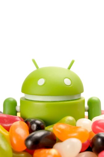 &quot;Forest Row, East Sussex, United Kingdom - June 7th 2012: Android phone mascot half buried in jellybeans. Shot in home studio on white.&quot;