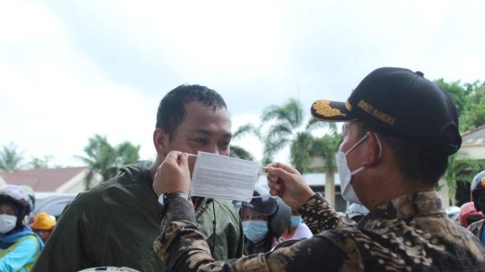 Bupati Bangka, Mulkan saat meninjau dan memberikan masker kepada para pengendara yang mengantre BBM di sejumlah SPBU di Kota Sungailiat, Bangka, Sabtu (12/12/2021).  