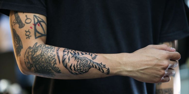 Pengunjung menunjukkan tato Karya seniman tato, I Putu Eka Mardiyasa saat acara live tattooing dan custom art painting bertajuk Ke Jakarta Vol. 2 di Ruang Selatan, Kemang, Jakarta Selatan, Sabtu (6/7/2019).(KOMPAS.COM/KRISTIANTO PURNOMO) 