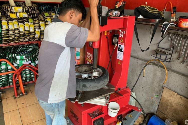 Ilustrasi teknisi sedang memasang ban motor pada pelek menggunakan mesin khusus.(KOMPAS.com/DIO DANANJAYA) 