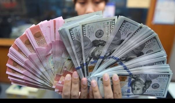Seorang pekerja menunjukkan uang rupiah dan dolar AS di sebuah tempat penukaran uang di Jakarta. 
