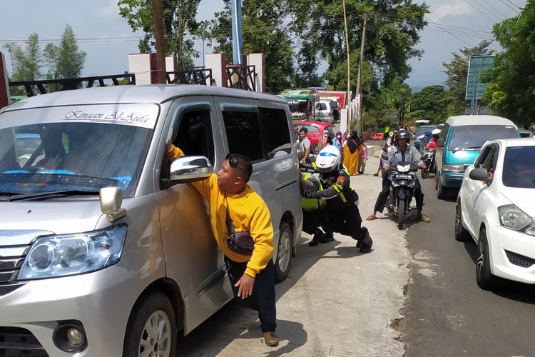 Polisi dan warga mendorong mobil yang mogok di jalur wisatawan Baturraden, Kabupaten Banyumas, Jawa Tengah, Kamis (5/5/2022).(KOMPAS.COM/FADLAN MUKHTAR ZAIN)