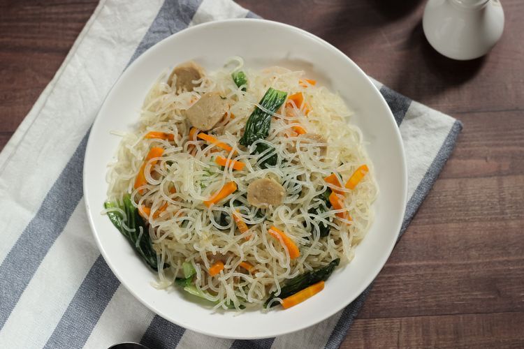 Ilustrasi bihun goreng putih dengan bakso dan sayuran pelengkap.  