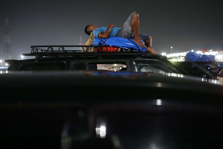 Pemudik tidur saat terjebak antrean panjang di Dermaga 7 Pelabuhan Merak, Cilegon, Banten, untuk naik ke kapal, Kamis (20/4/2023). Kantong parkir di tujuh dermaga yang tersedia sejak Rabu (19/4/2023) malam hingga Kamis (20/4/2024) pagi kembali dipenuhi mobil kendaraan pemudik yang akan menyeberang ke Sumatera.(KOMPAS.com/KRISTIANTO PURNOMO) 