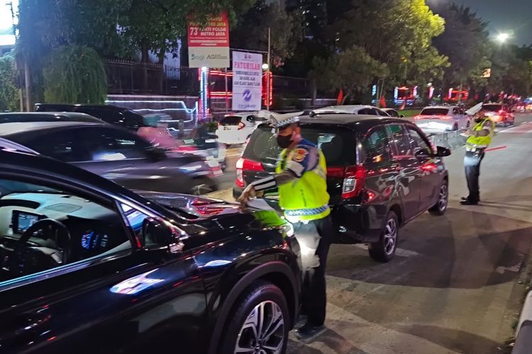 Polisi sedang menilang beberapa pengendara di Jalan Gatot Subroto, depan pintu masuk SCBD, Jakarta Selatan, Selasa (16/5/2023).(KOMPAS.com/RIZKY SYAHRIAL)  