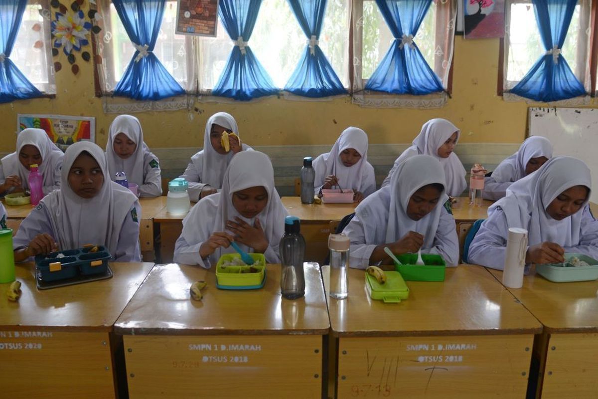 Sejumlah siswa menyantap makan siang gratis di SMP Negeri-1 Darul Imarah, kabupaten Aceh Besar, Aceh, Selasa (5/3//2024). Pemerintah Kabupaten Aceh Besar melaksanakan simulasi program makan siang gratis untuk pelajar dengan lima jenis makanan bergizi dan sehat senilai Rp15 ribu per porsi. ANTARA FOTO/Ampelsa/Spt.