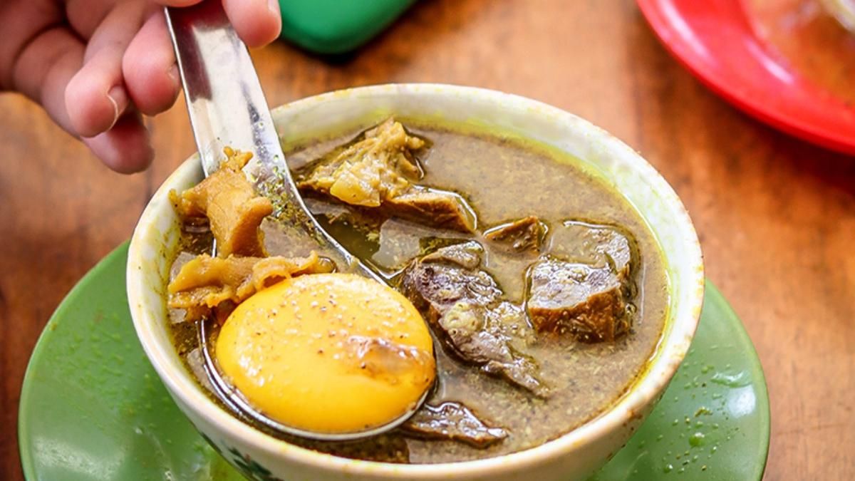 Semangkuk Pallubasa Daging Sapi khas Makassar dengan kuah rempah yang kental, disajikan dengan kuning telur mentah dan taburan bawang goreng